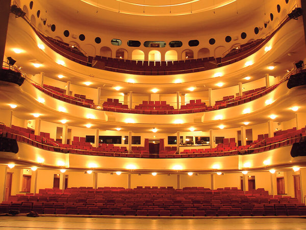 The theatre hall of the Großes Haus in the Braunschweig State Theatre with a view from the stage of the empty, pleasantly lit hall with stalls and three tiers.