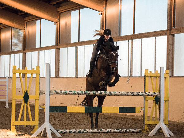 A rider jumps over an obstacle in an indoor arena. Announcements from the judges do not bother humans and especially animals, as the speakers from the Pan AMT series have a natural and authentic sound.